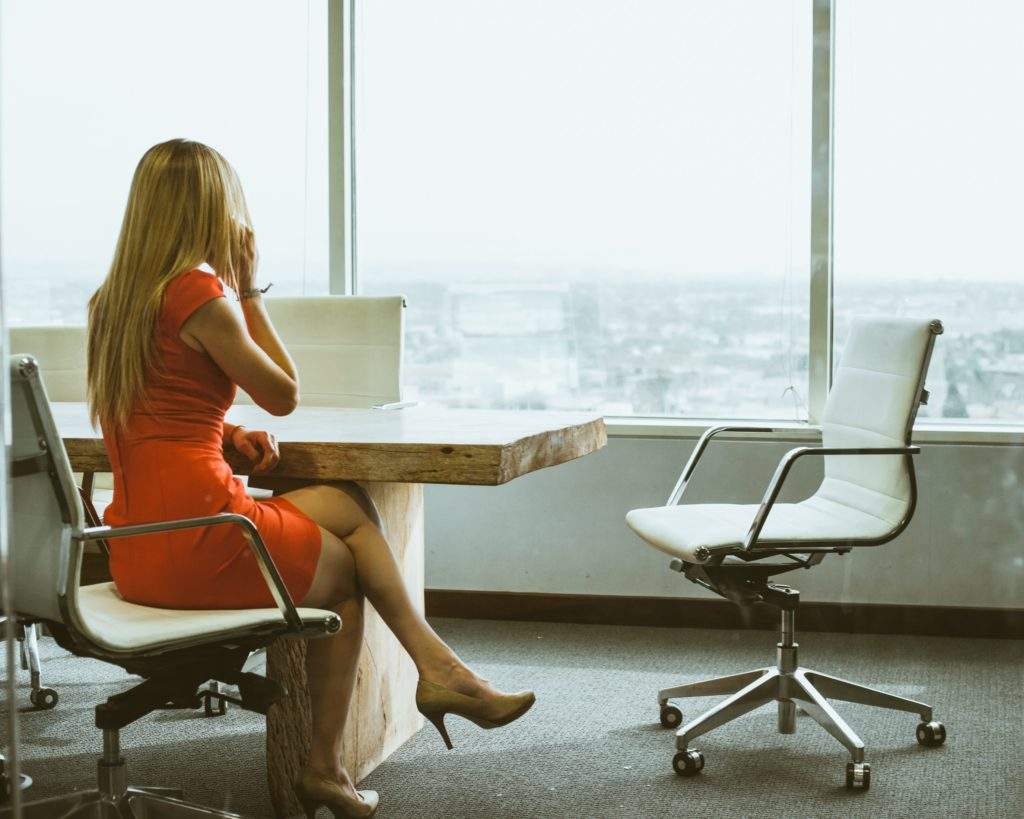 Business woman in professional orange dress at desk in high rise office