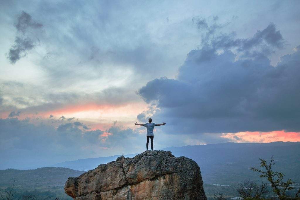 person standing in success at the top of a mountain